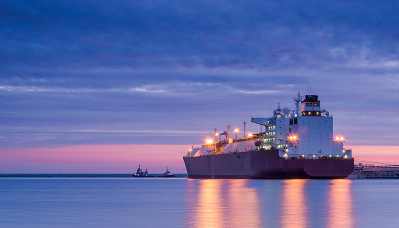 Featured Image. Cargo Ship sailing on the ocean as the sun sets