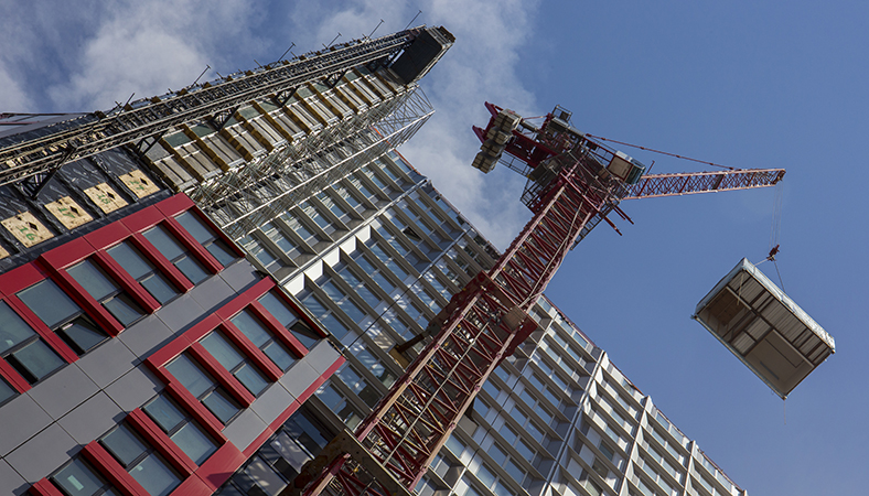 Featured Image. A crane lifting equipment on alongside a high-rise building