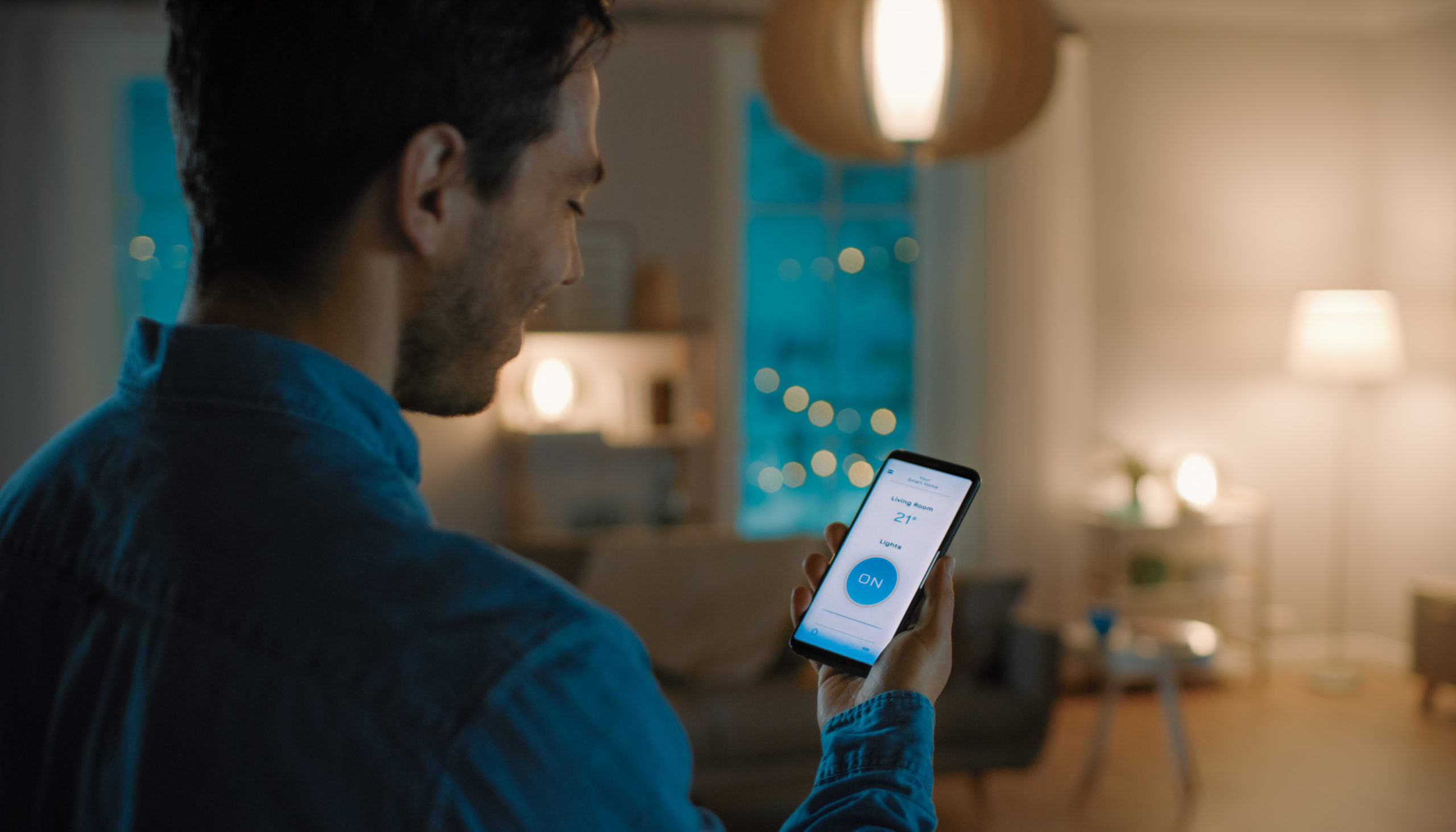 L'image sélectionnée. Man Gives a Voice Command to a Smart Home Application on His Smartphone To Switch on the Lights