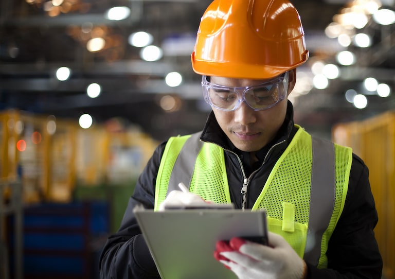 Un travailleur dans une installation industrielle écrivant des notes